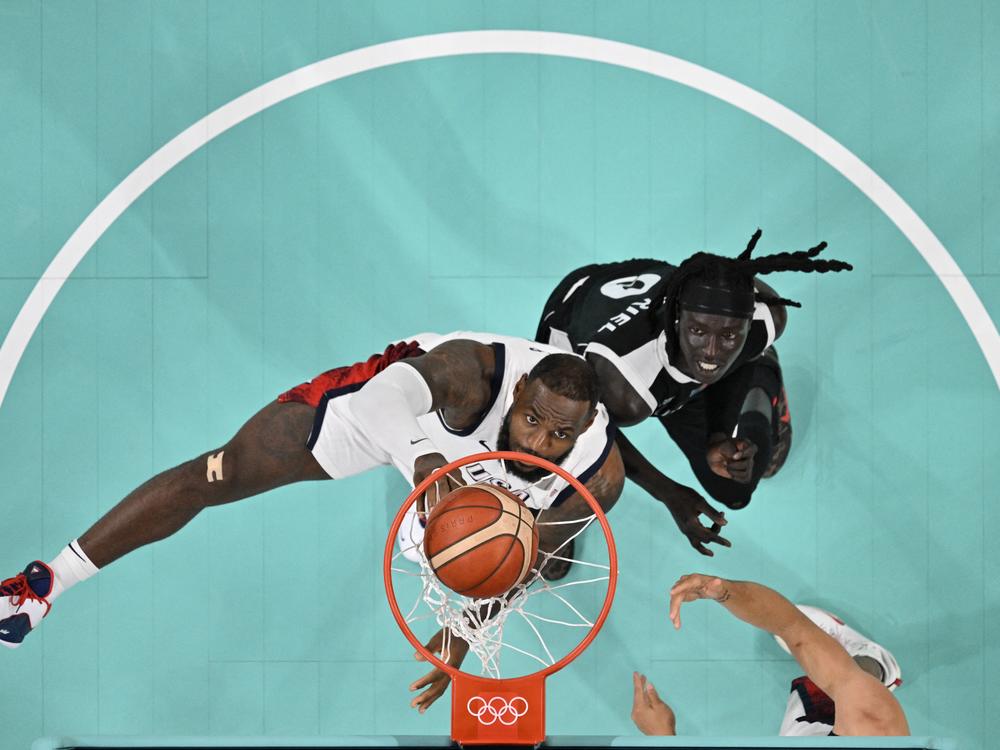 LeBron James, on Team USA, and South Sudan's Wenyen Gabriel eye the ball in the men's preliminary round Group C basketball match Wednesday.