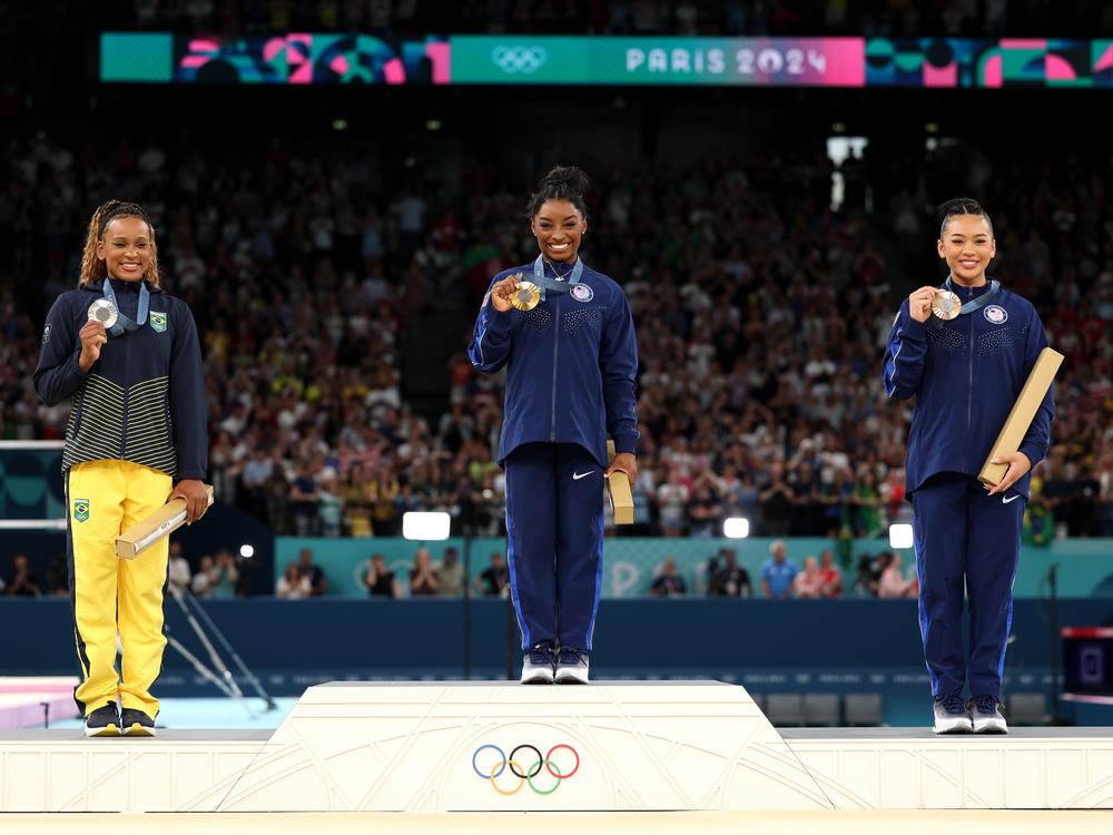 Gold medalist Simone Biles of the United States (center) is flanked by silver medalist Rebeca Andrade of Brazil (left) and bronze medalist Sunisa Lee of the U.S. These medals were awarded for the all-around category on August 1.