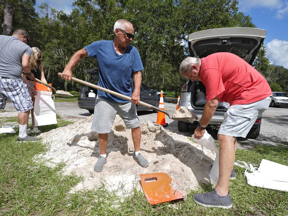 Roger Heim (right) and Terry Smith (second from right), both of Valrico, Fla., fill sandbags in preparation for the weekend storm at the Edward Medard Conservation Park in Plant City, Fla.