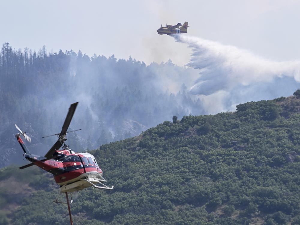 A CL 415 scooper, top, drops water on the Quarry Fire as a Firehawk helicopter maneuvers for a water drop Thursday, southwest of Littleton, Colo. 