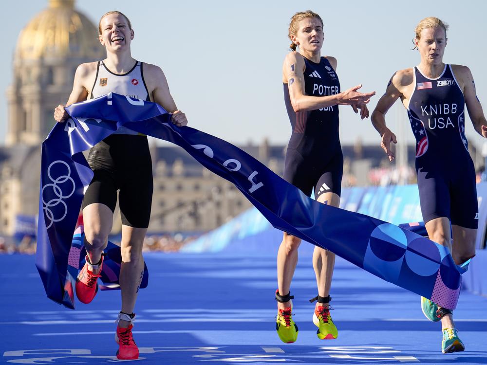 Germany's Laura Lindemann, left, celebrates after winning the gold medal next to silver medalist Great Britain's Beth Potter, center, and bronze medalist Taylor Knibb, of the U.S., right, at end of the mixed relay triathlon on Monday in Paris.