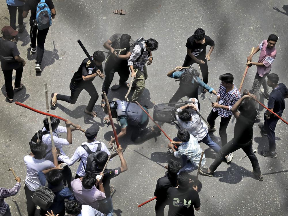 Students beat a policeman with sticks during a protest on July 18