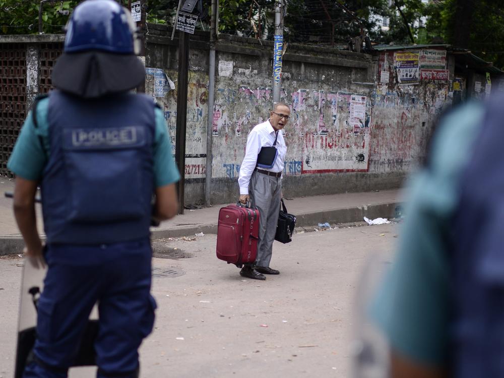 A passerby talks to police during a curfew imposed after scores were killed and hundreds injured in clashes over the allocation of civil service jobs on July 21.