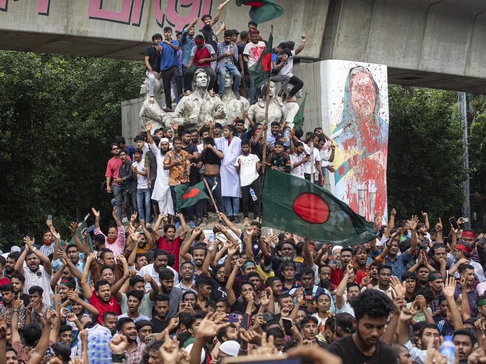 Protesters climb a public monument as they celebrate the news of Prime Minister Sheikh Hasina's resignation on August 5.
