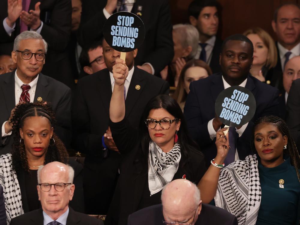 U.S. Rep. Rashida Tlaib, D-Mich. (C) and Rep. Cori Bush,D-Mo. hold up signs as President Joe Biden delivers the State of the Union address at the U.S. Capitol on March 7, 2024 in Washington, D.C.