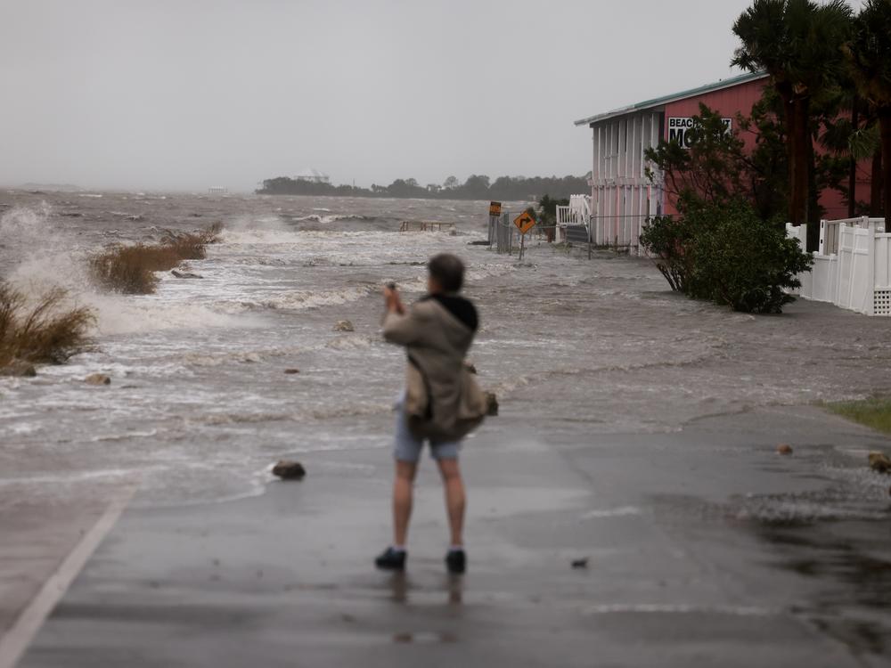 A person looks at a flooded street caused by the rain and storm surge from Hurricane Debby on Monday in Cedar Key, Fla. Hurricane Debby is now moving slowly over Georgia, bringing heavy rain storms and high winds along the coast.