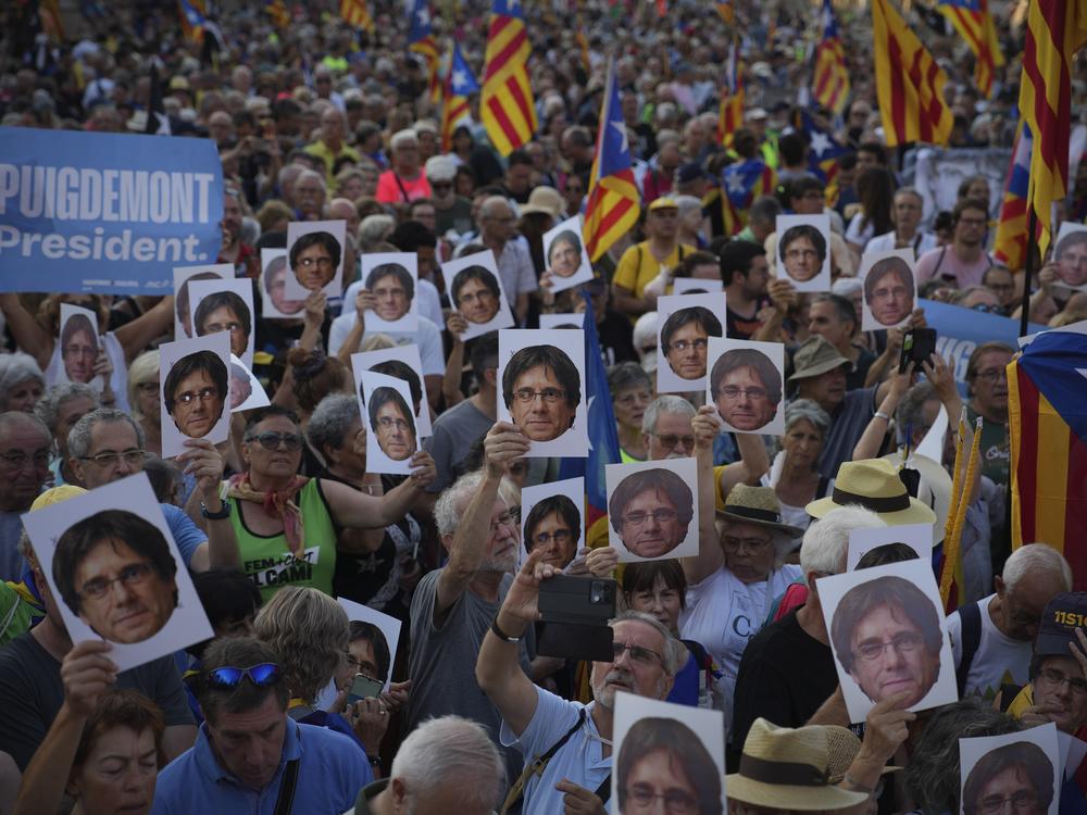 Supporters of Catalan independence leader Carles Puigdemont hold his portrait as they wait for his arrival near the Catalan Parliament on Thursday.