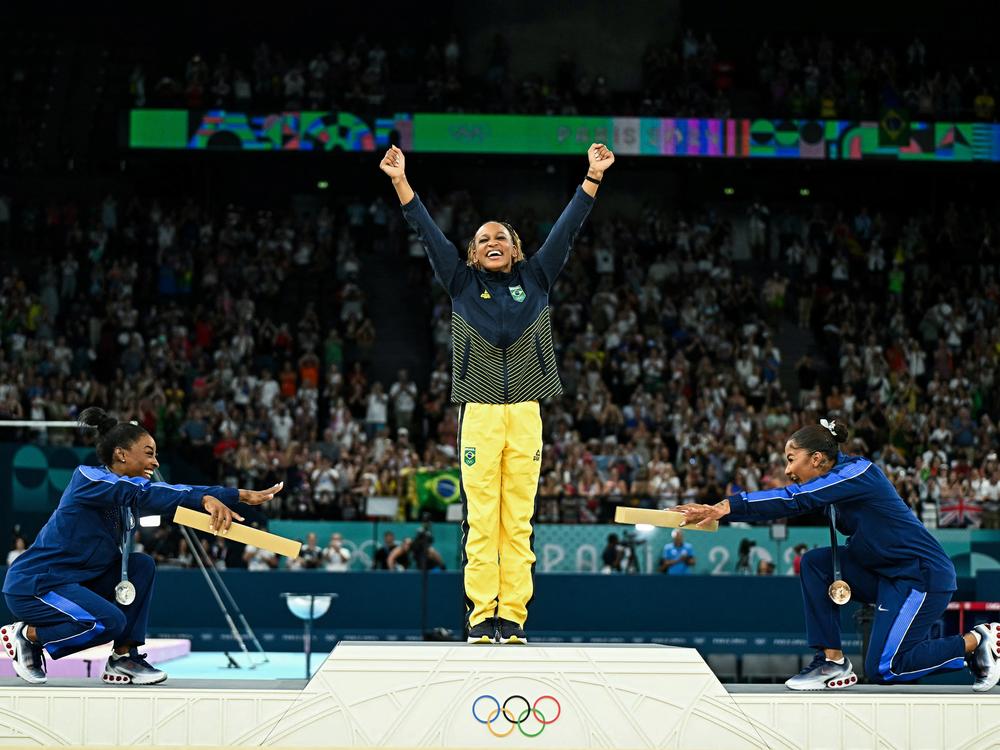 Simone Biles, left, joins teammate Jordan Chiles in pointing toward gold medalist Rebeca Andrade of Brazil. Biles won silver and Chiles bronze in the women's floor exercise at the Paris 2024 Olympic Games — the first time three Black athletes have shared the podium in Olympic gymnastics.