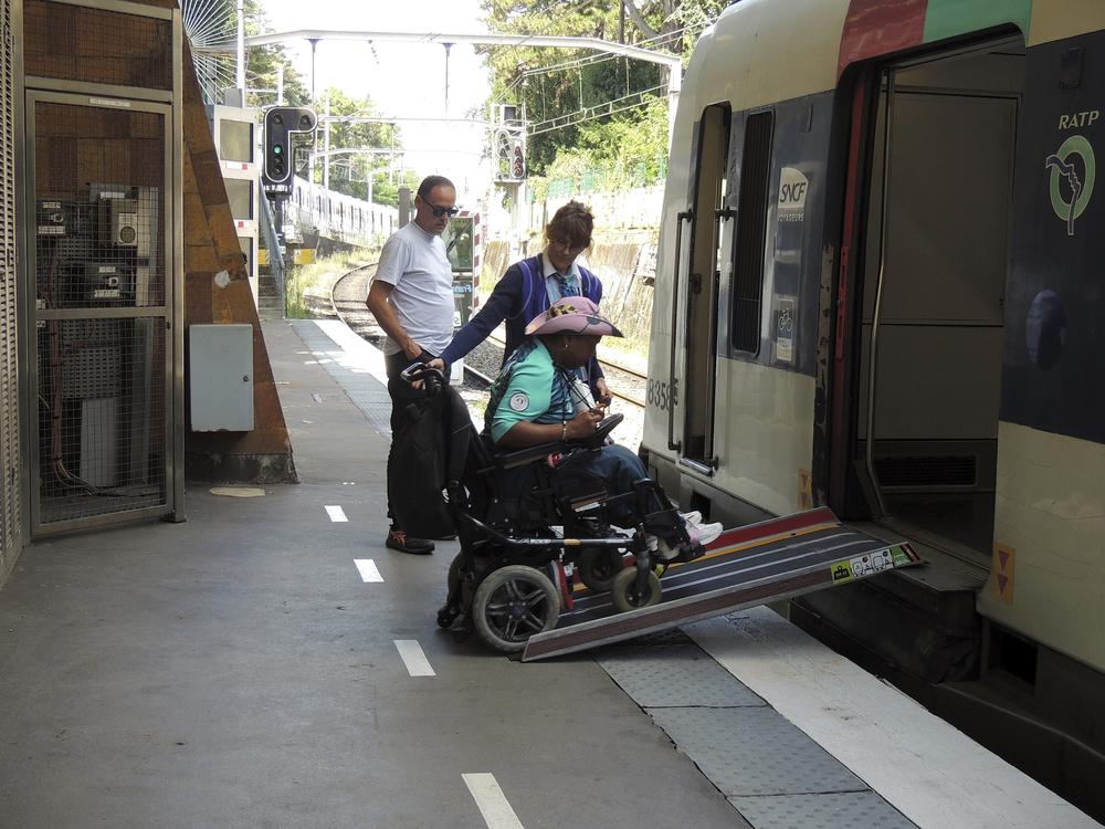 Ndieme Lame, a 57-year-old volunteer for the Paris 2024 Olympic and Paralympic Games navigates a ramp to join a RER train with the help of rail agents, during the 2024 Summer Olympics, on Wednesday in Paris, France. 