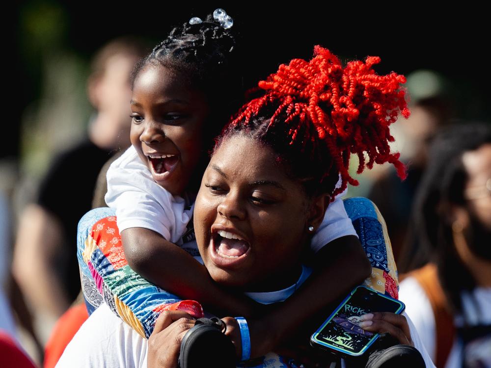 Trinaya’ Walker, 22, holds her daughter Bobbie Ann Atkins, 6, during the unity march.