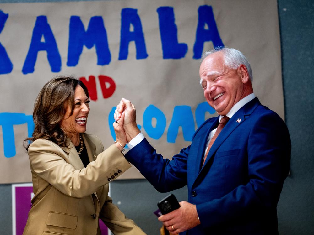 Harris and Walz laugh after taking a selfie in front of a sign that reads 