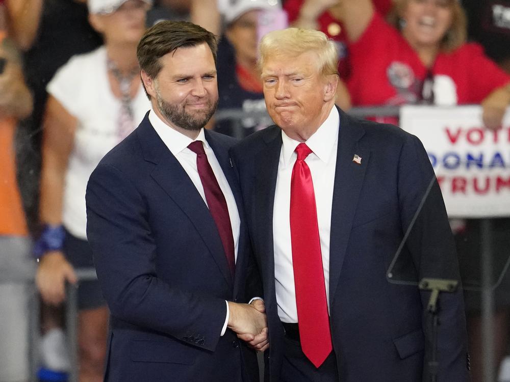 Former President Trump and his running mate, Sen. JD Vance of Ohio, shake hands at a campaign rally at Georgia State University in Atlanta, on Aug. 3, 2024. 