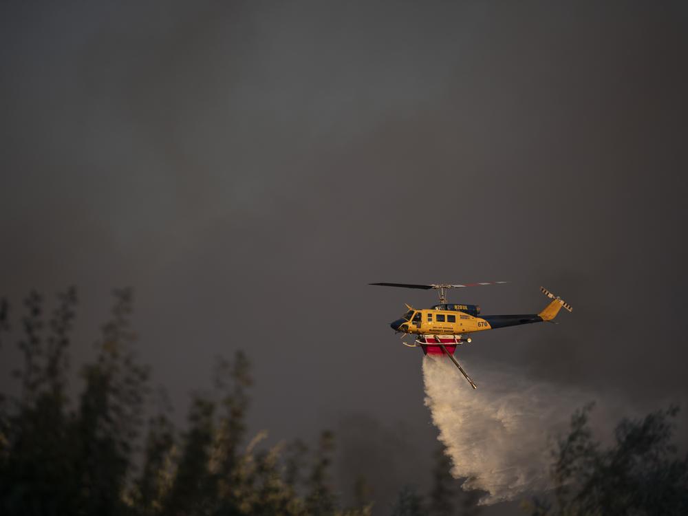 A helicopter drops water near Varnava village during a wildfire, north of Athens, Greece, on Sunday, with many regions of the country on high alert due to high temperatures and wind speeds.