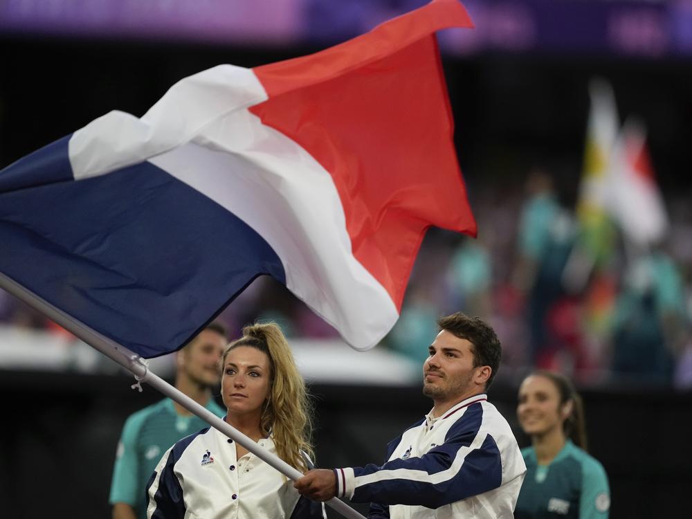 Athletes wave a French flag during the 2024 Summer Olympics closing ceremony at the Stade de France, Sunday.