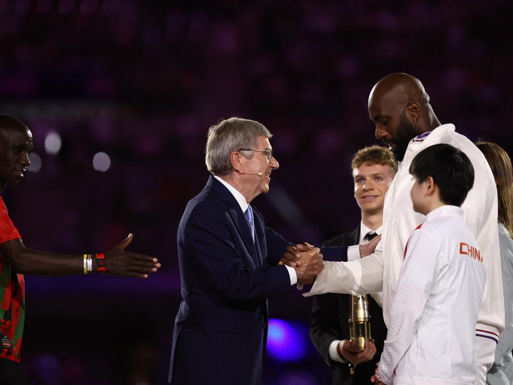 International Olympic Committee President Thomas Bach (center) shakes hands with France's judoka Teddy Riner on Sunday.
