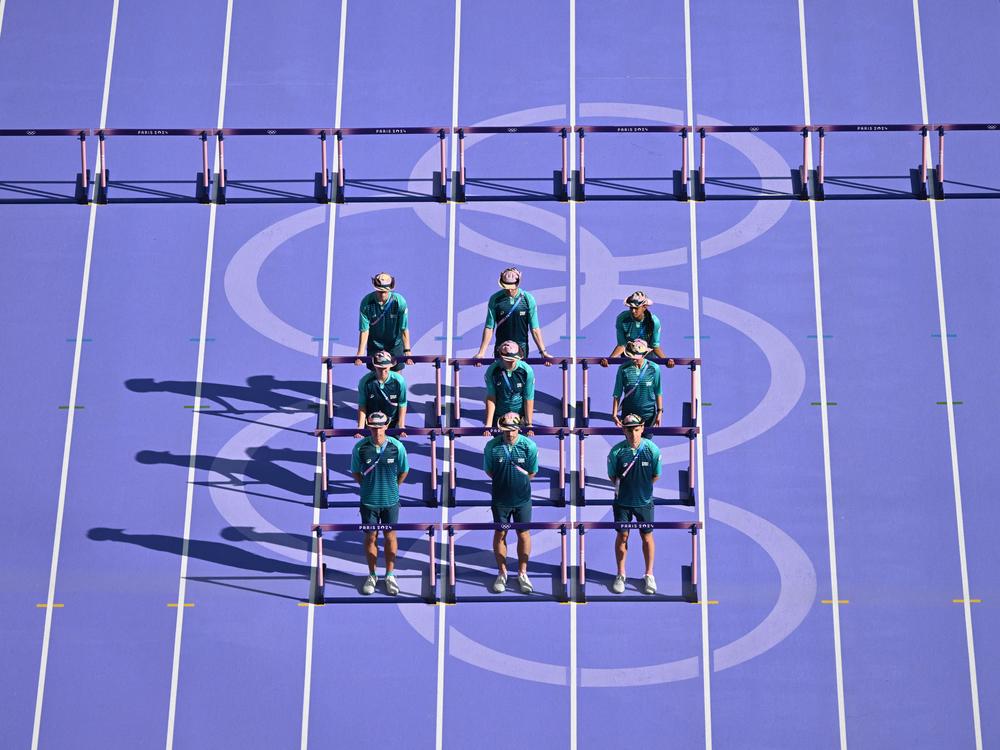 Volunteers transport the hurdles ahead of the women's heptathlon 100m hurdles event at Stade de France in Saint-Denis, north of Paris.