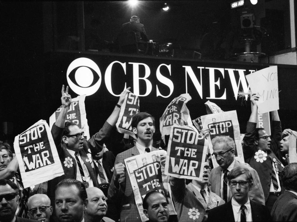 As they stand in front of the CBS News booth, protesters hold up 'Stop the War' signs on the floor of the Democratic National Convention in the International Amphitheatre, Chicago, Aug. 28, 1968.