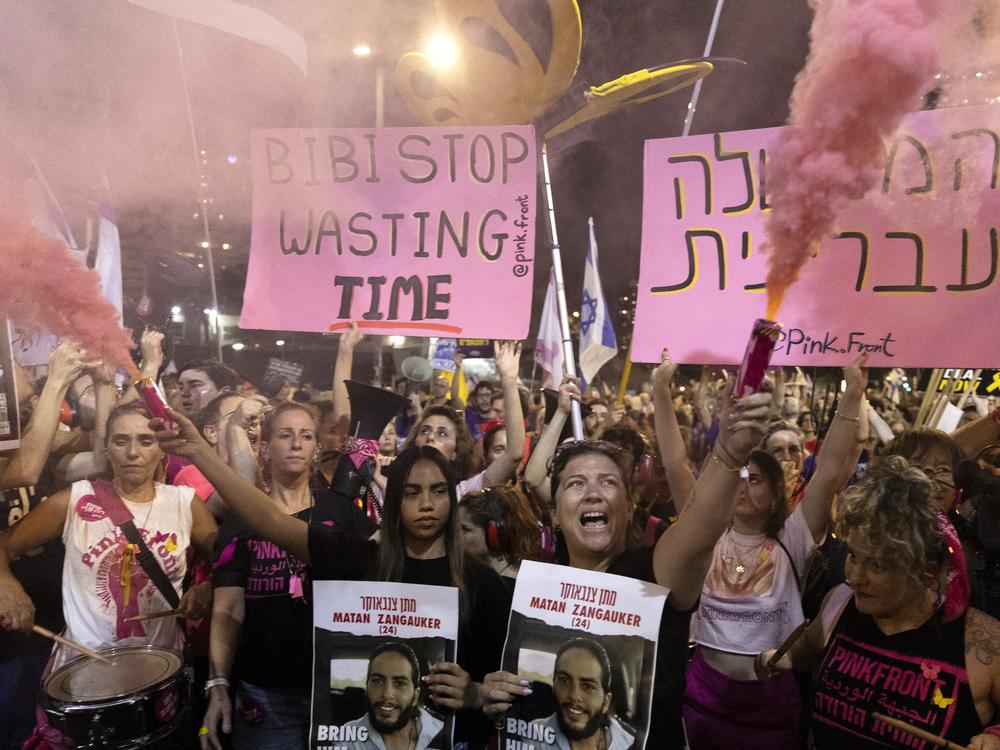 Protesters hold signs and smoke torches  during a demonstration calling for an hostages deal and against Israeli Prime Minister Benjamin Netanyahu and his government on August 10.