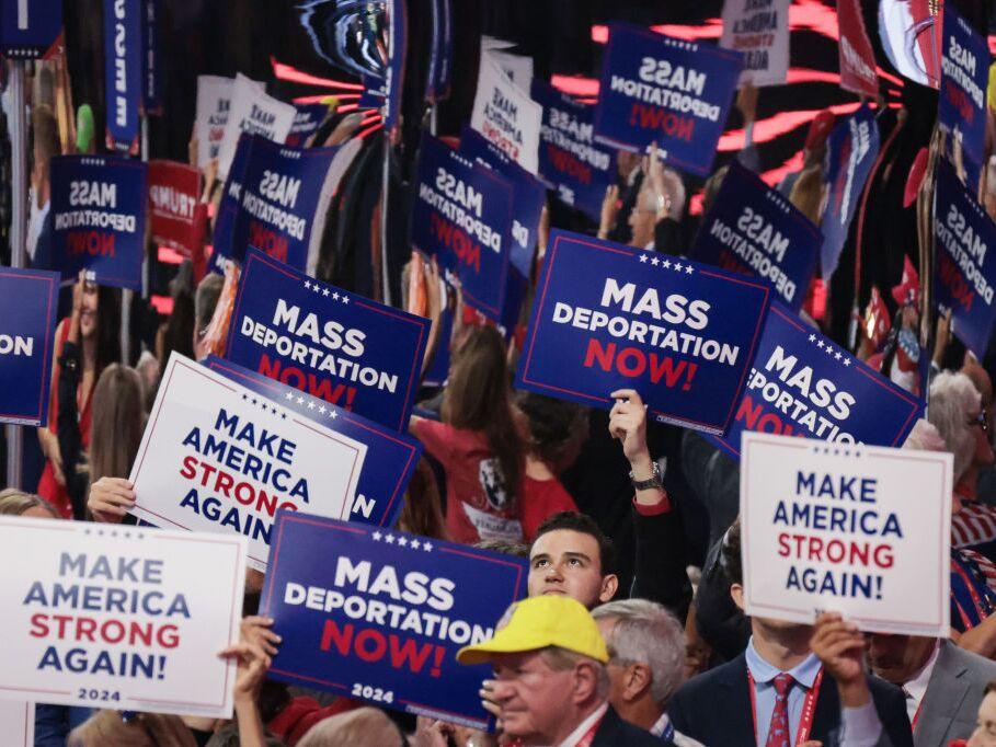 Attendees at the Republican National Convention hold up signs reading 