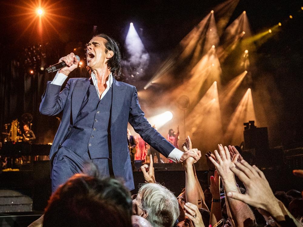 Nick Cave on stage with The Bad Seeds. After the accidental death of his son Arthur, in 2015, Cave forged a different relationship with his fans through correspondence and live conversation.
