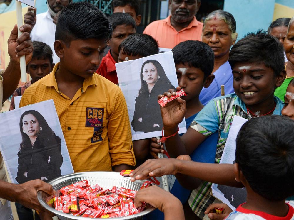 Villagers holding photos of Kamala Harris distribute sweets to celebrate Harris' inauguration as U.S. vice president in January 2021, in Harris' ancestral village of Thulasendrapuram.
