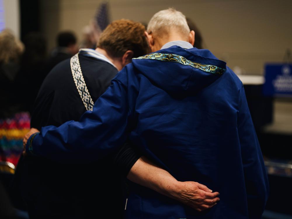Two attendees hold each other during an opening prayer at the Native American caucus meeting on August 19, 2024. Grace Widyatmadja/NPR