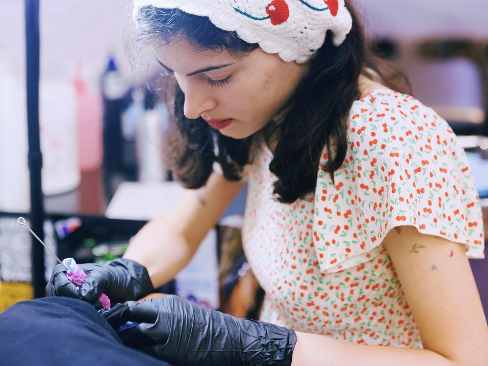 Abby Ingwersen, a guest artist at Nice Try Tattoo, works on a client using the stick and poke method.