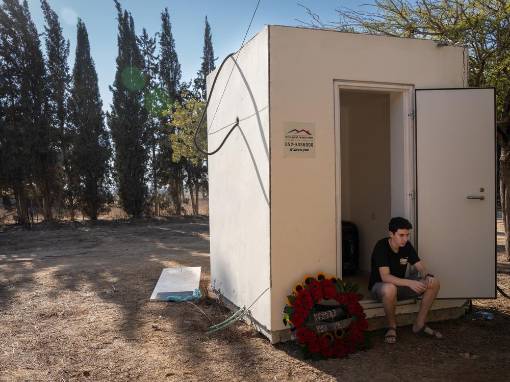 A boy sits beside a wreath that reads 
