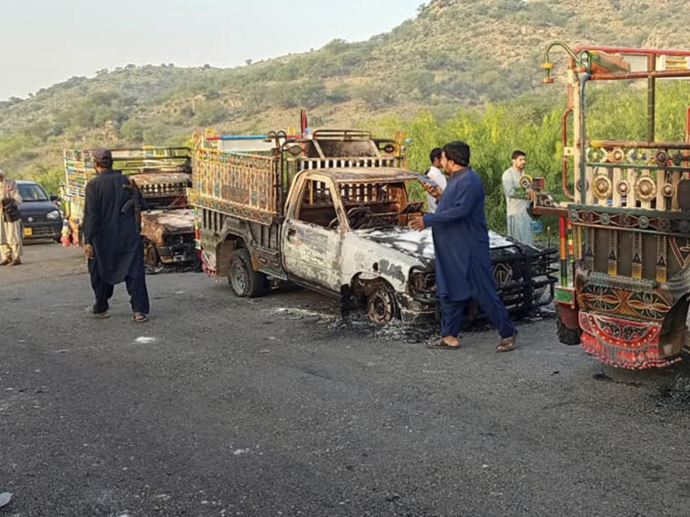 People near burned vehicles, torched by gunmen after killing passengers, on a highway in Musakhail, a district in Baluchistan province in southwestern Pakistan on Monday.
