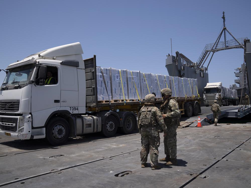 U.S. Army soldiers stand next to trucks arriving loaded with humanitarian aid at the U.S.-built floating pier Trident before reaching the beach on the coast of the Gaza Strip, June 25, 2024.