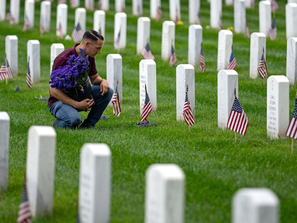 A man places flowers in front of headstones in Section 60, which mark the final resting place of service men and women at Arlington National Cemetery on May 27 in Arlington, Va.