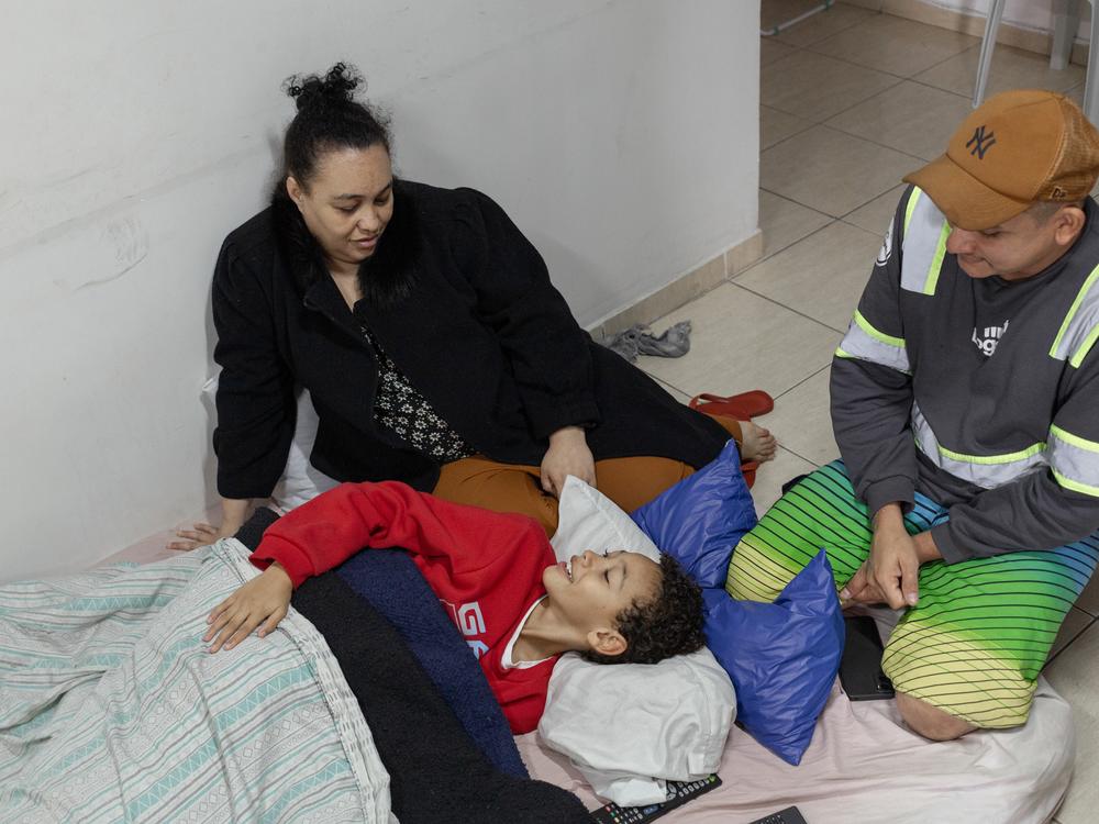 Erica Lacerda de Souza, her son, Henrique, and her husband, Bruce Lee de Souza, relax in their new home in Guaianazes, São Paulo. 