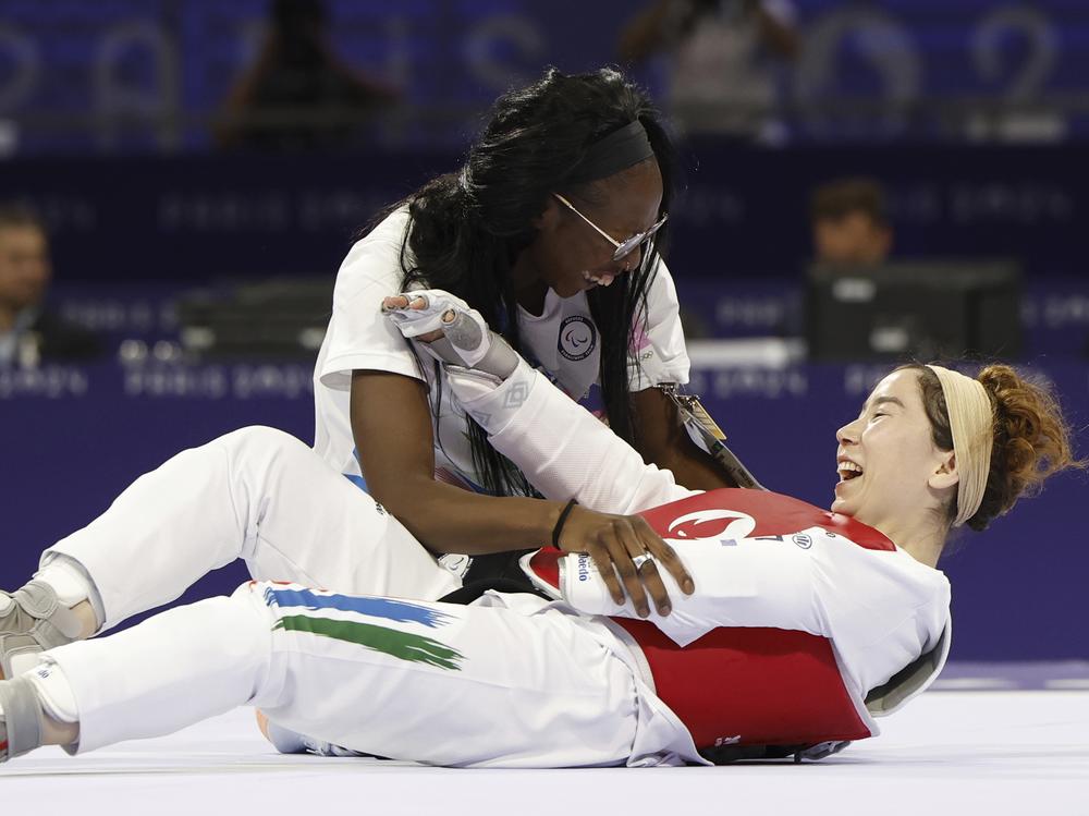 Zakia Khudadadi from the Paralympic Refugee Team, bottom, celebrates her bronze medal in Para Taekwondo during the Paralympic Games in Paris, Thursday, Aug. 29, 2024. 