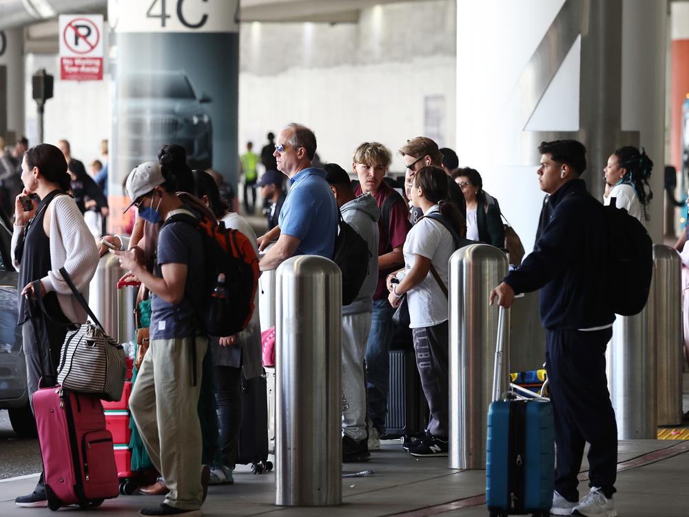 Travelers await rides at Los Angeles International Airport ahead of the Labor Day holiday on Friday.