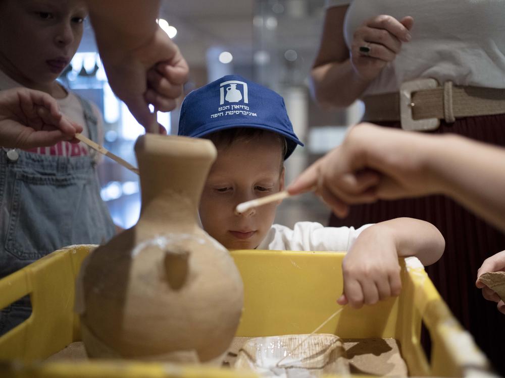 Ariel Heller, 4, helps to glue a broken clay jar during a special tour with his family after he accidentally broke another jar at the Reuben and Edith Hecht Museum in Haifa, Israel, on Friday. The boy who accidentally broke a rare 3,500-year-old jar in an Israeli museum has been forgiven and invited back, as curators hope to turn the disaster into a teachable moment.