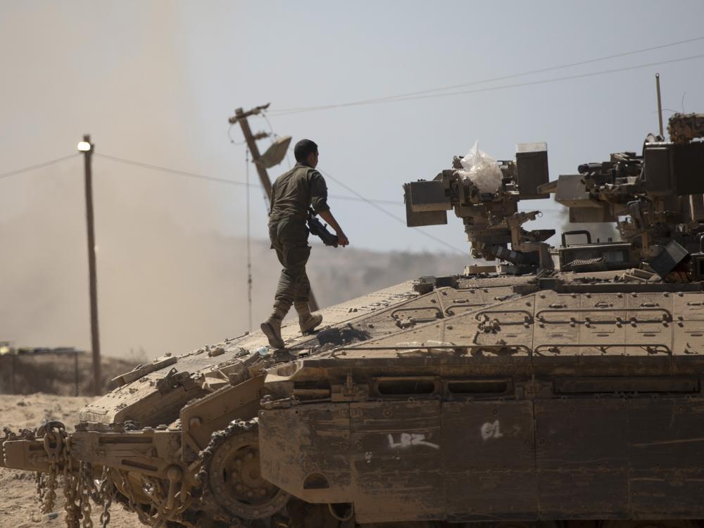 An Israeli soldier walks on a tank near the border of the Gaza Strip in southern Israel on Aug. 21.