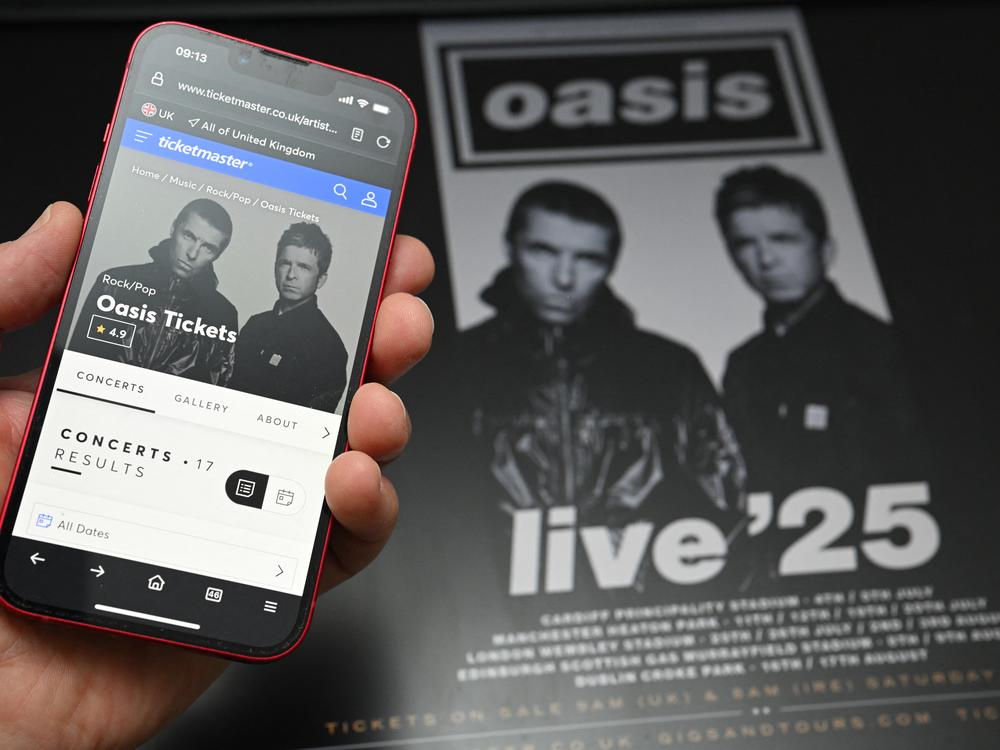 A fan uses a smartphone to access an online ticket sales website to purchase tickets for Oasis' 