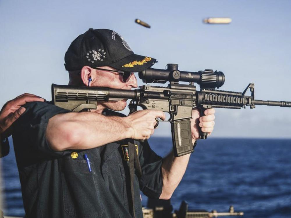 This undated photo, provided by <em>Stars and Stripes</em>, shows Cameron Yaste, commanding officer of the destroyer USS John McCain, firing a rifle with a backwards scope.