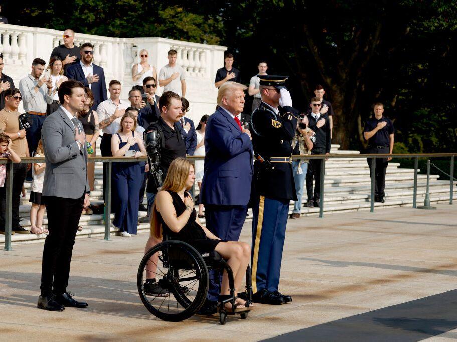 Former President Donald Trump looks on alongside Marlon Bateman (left), Marine Cpl. Kelsee Lainhart and U.S. Marine Corps Sgt. Tyler Vargas-Andrews during a wreath-laying ceremony at Arlington National Cemetery on Aug. 26 to honor the lives of those who died at the Abbey Gate bombing in Afghanistan.