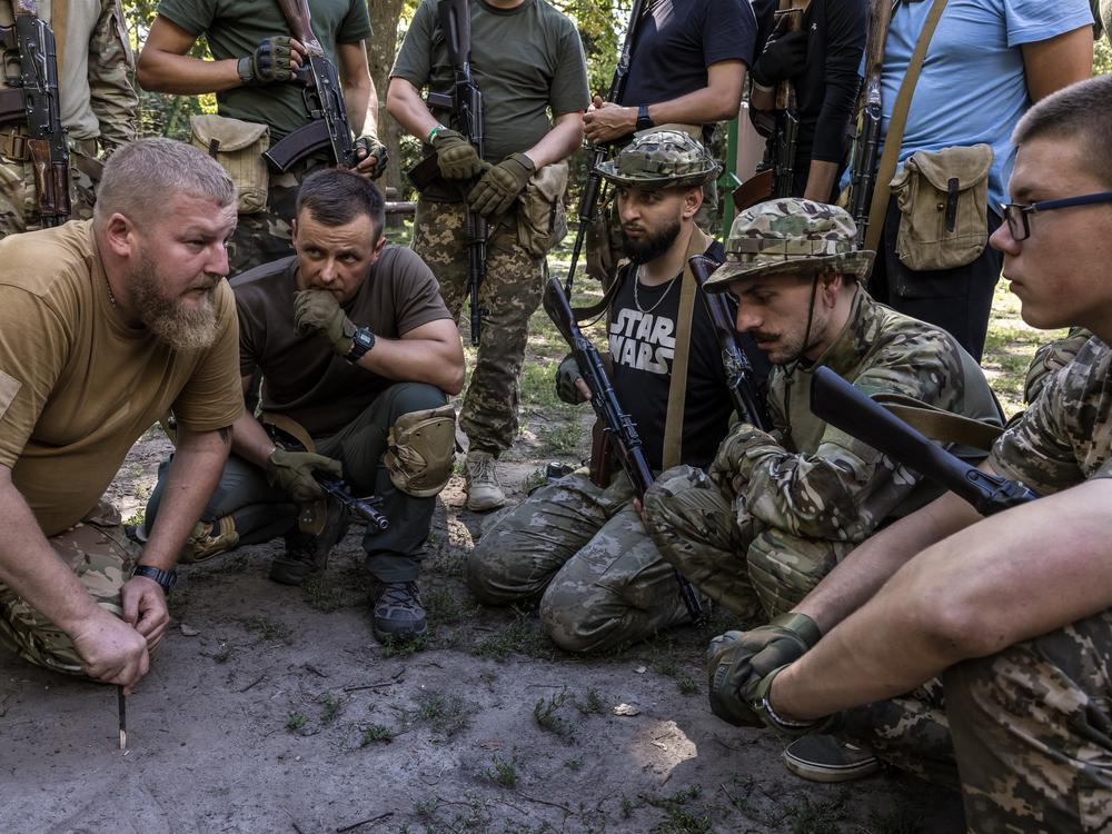 Ukrainians discuss the tactics of working in small groups at the military training called 