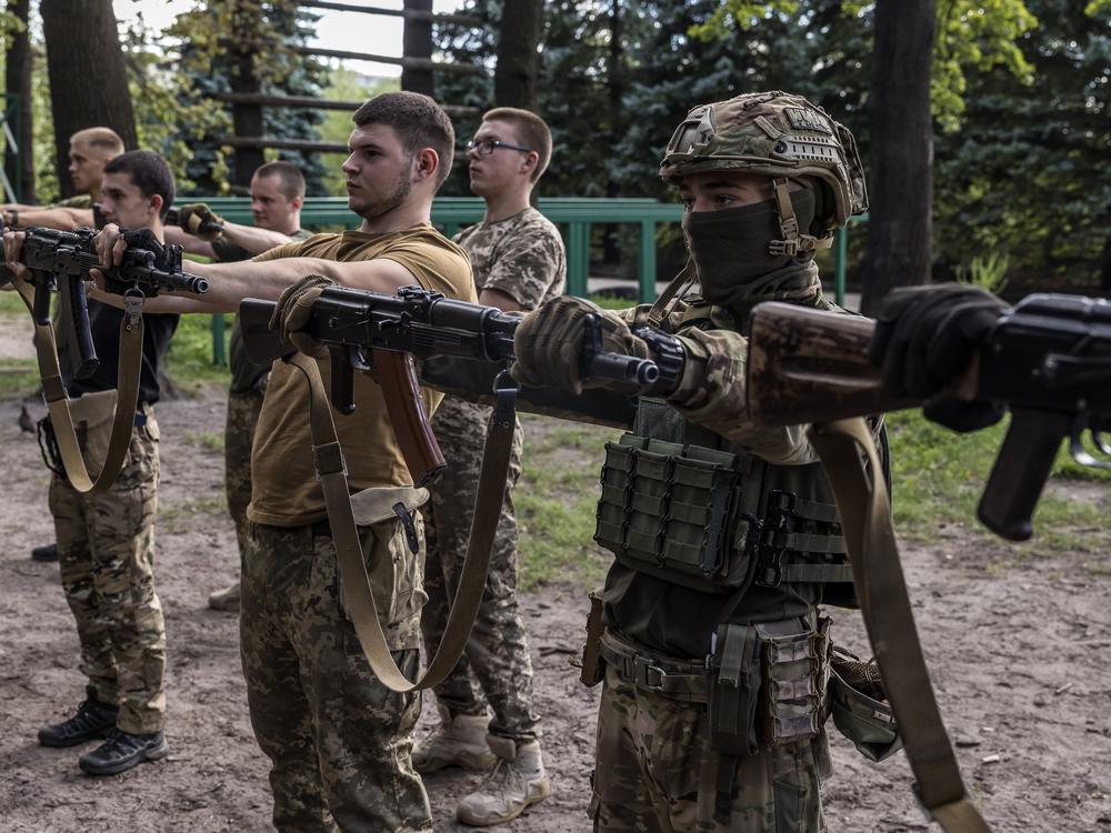 Ukrainian participants do an exercise holding a rifle as long as possible with straight arms in the military's 