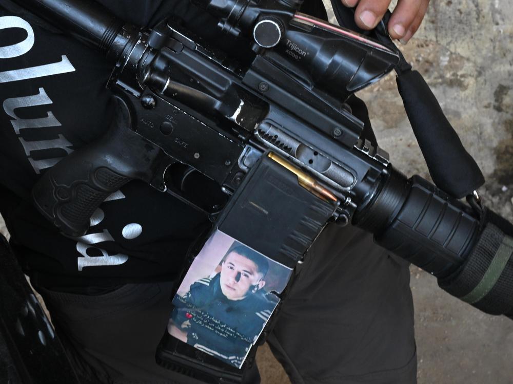 In Jenin refugee camp, a fighter shows a photo on his gun he says is a reminder of another young fighter who was killed by the Israeli army.