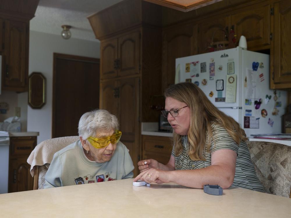 Kyla Sanders, the program coordinator for the Western Morton County Aging in Community program, helps program participant Leona Staiger, 94, set up a medical alert device at her home in Hebron, N.D., on May 23. Sanders wears many hats in her role.