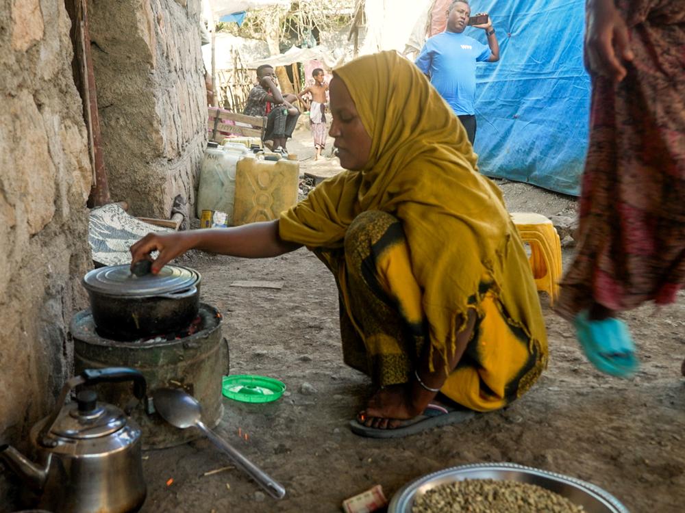 <em>Fatouma Zahara Hasan heats water at the front of her home where she sells traditionally made Ethiopian coffee in the town of Chifera, in Ethiopia's Afar region.</em>