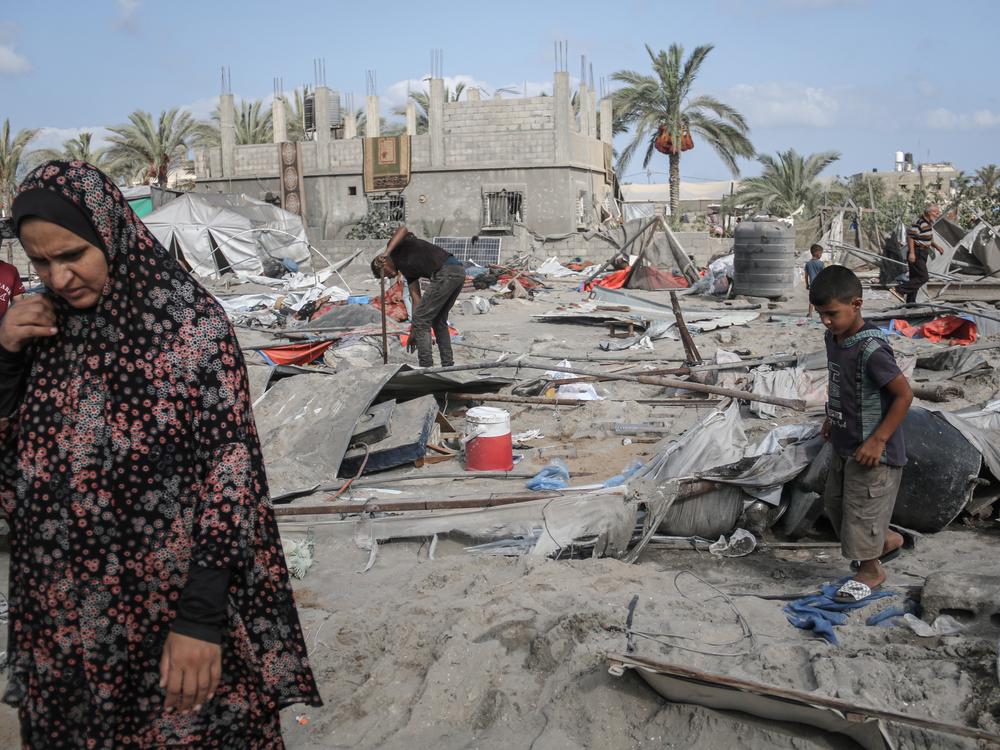 Palestinians look at the destruction following an Israeli airstrike in al-Muwasi, a designated humanitarian zone in Khan Younis, southern Gaza, on Tuesday. The Israeli military said it was targeting a Hamas command and control center and killed three Hamas commanders in the strike. Hamas did not confirm the deaths.