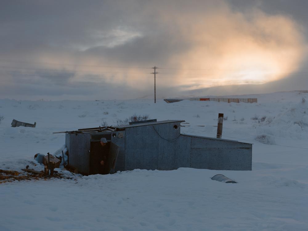 CANHR lead investigator and Qungasvik community organizer Simeon John goes to collect water outside his Maqi (steam house) near his home in Toksook Bay, Alaska. Historically, he says that the steam bath has played an important role in mental wellness within the community by providing neighbors with spaces to gather and share their concerns.<br />

