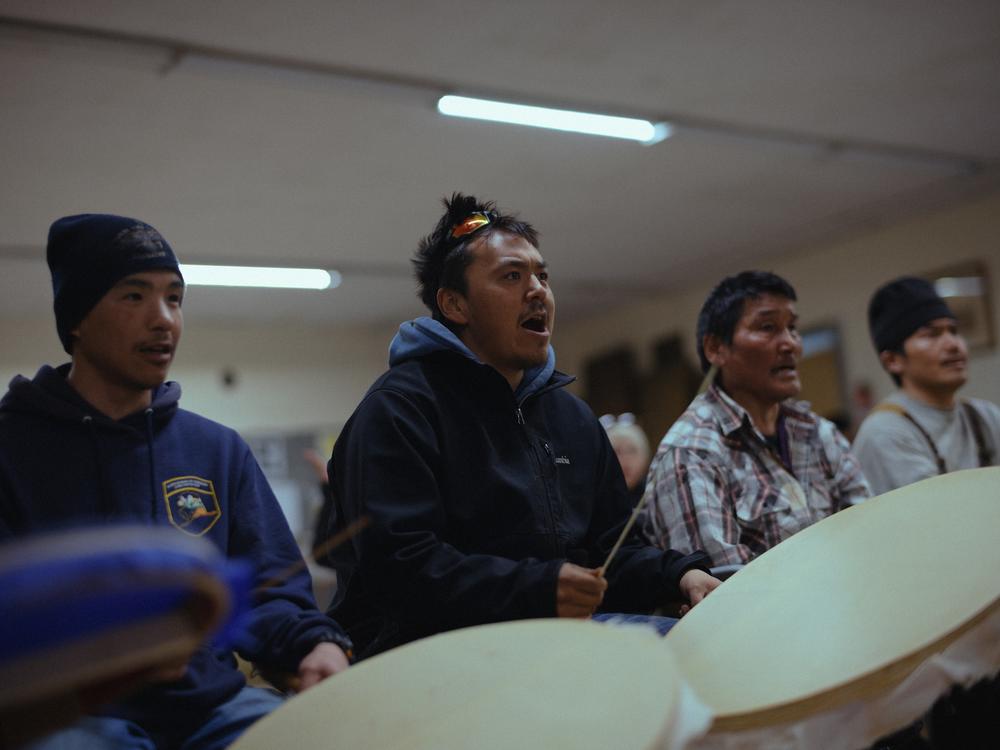 Gideon Green (center) sings with a group of drummers at a Yup’ik dance practice in Hooper Bay that’s been supported by Qungasvik. For Green, who has lost several close friends to suicide, the group has proven integral to his healing. 