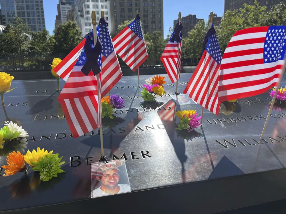 Flags and flowers are placed by the names of those killed during the Sept. 11, 2001, attacks, at the reflecting pools at the National September 11 Memorial & Museum, Tuesday, Sept. 10, 2024, in New York.