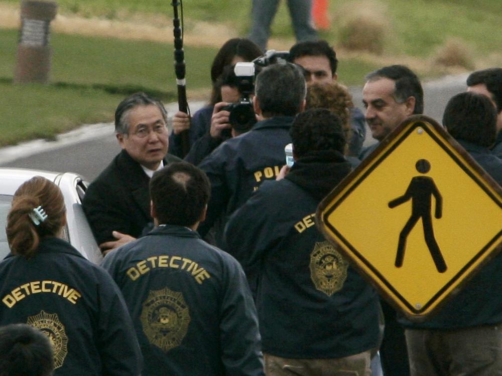 Chilean police officers surround former Peru's President Alberto Fujimori (left) as he leaves his house in Santiago to be extradited to Peru to face human rights and corruption charges, early Sept. 22, 2007. 