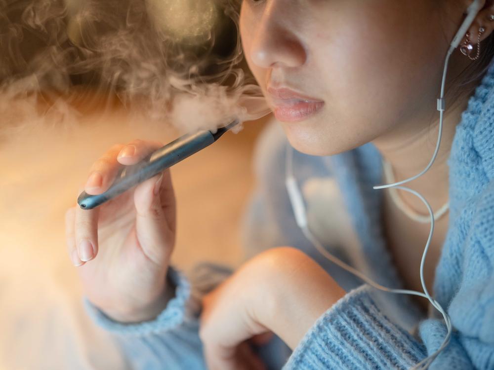A young woman vapes an electronic cigarette. Some districts are installing high-tech vape detectors to alert school officials if students are using e-cigarettes.